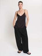 Model wearing the satin Camisole in black and Pleated pants in black