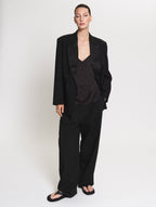 Model wearing the satin Camisole in black together with the Pleated pants in black and the Smoking blazer in black 