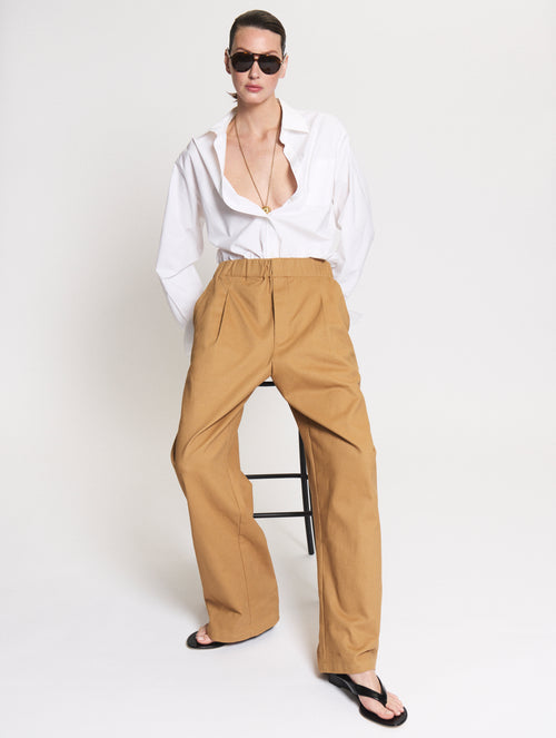 Model wearing a Body shirt in white together with the Utility pants in camel. 