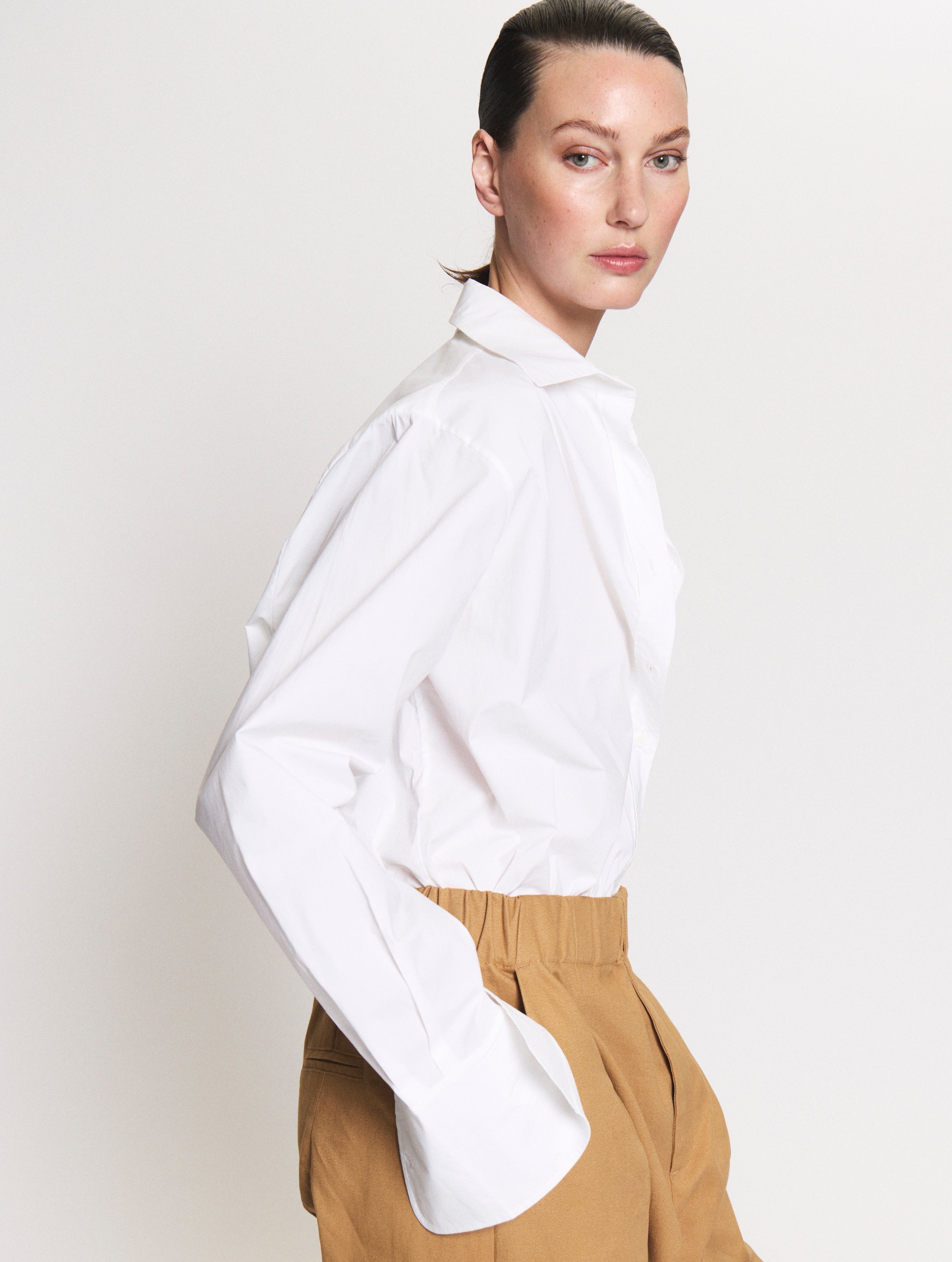 Detail shot of model wearing a Body shirt in white together with the Utility pants in camel. 