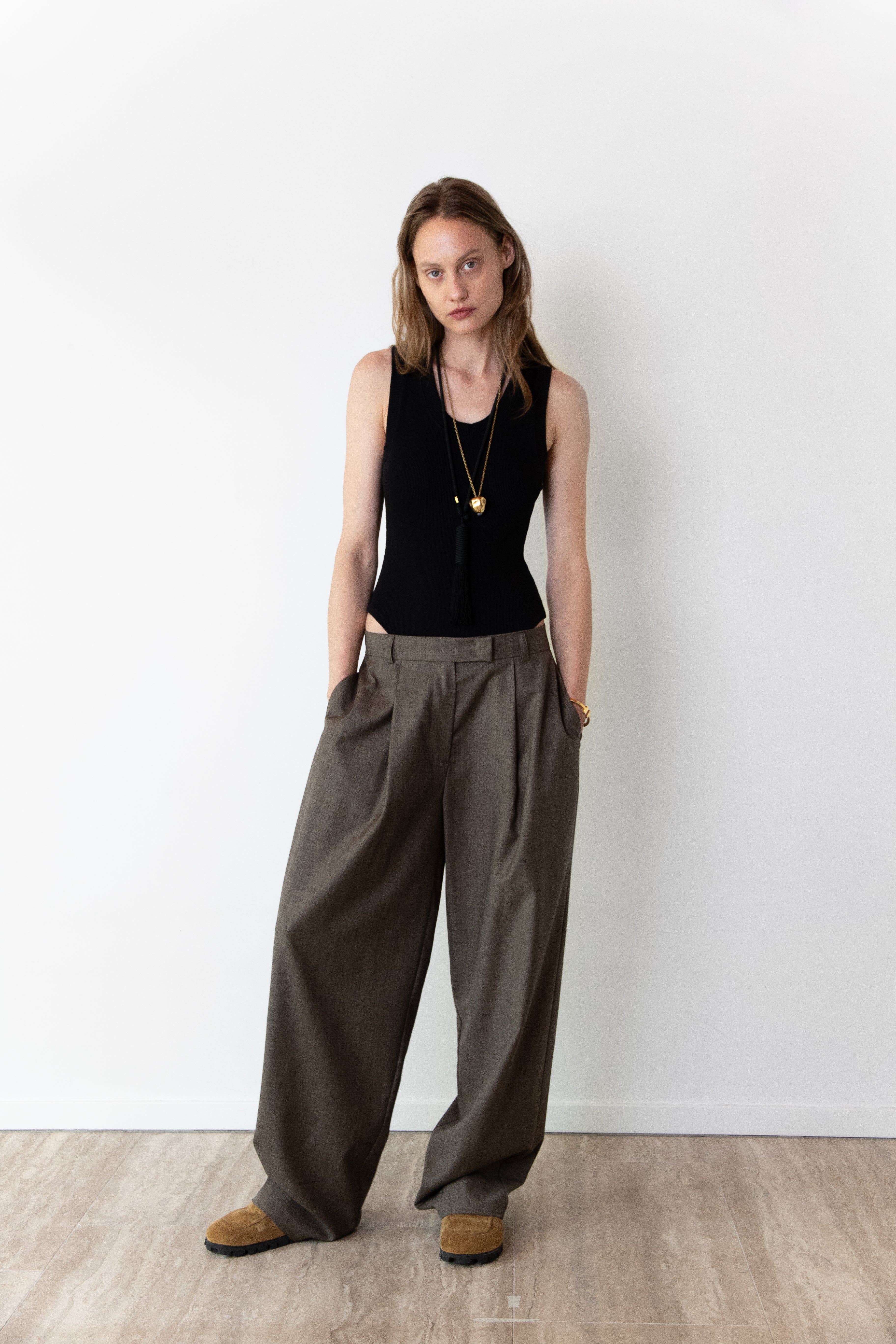 Model wearing the Tanktop body in black and the Limited Pleated pants in taupe