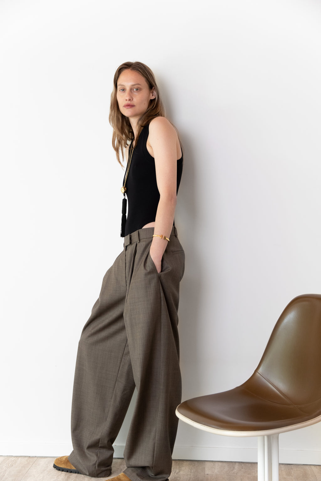 Side view of model wearing the Tanktop body in black and the Limited Pleated pants in taupe