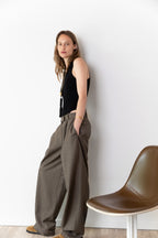 Side view of model wearing the Tanktop body in black and the Limited Pleated pants in taupe